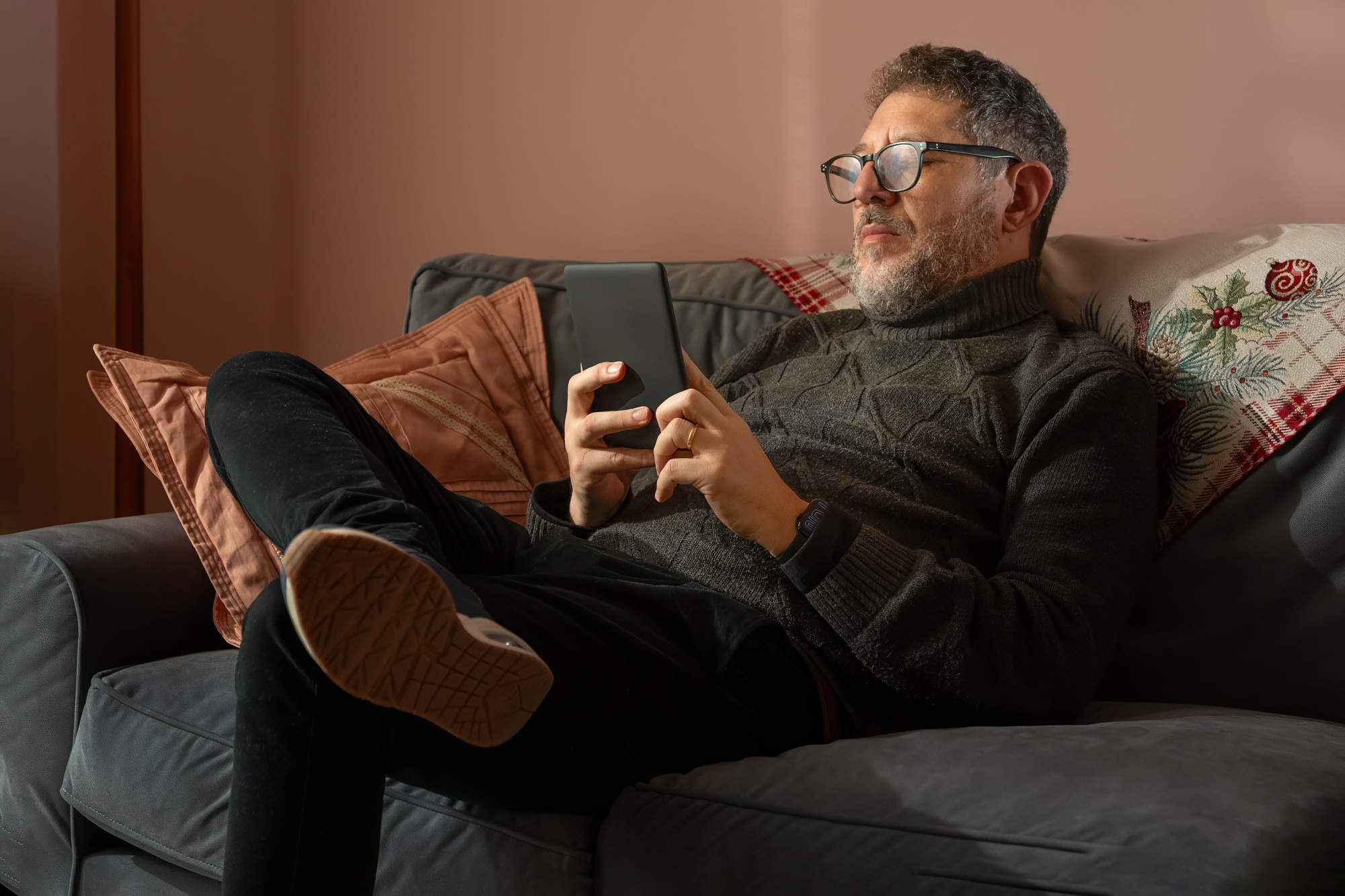 A man is sitting on a couch with an ebook reader in his hand