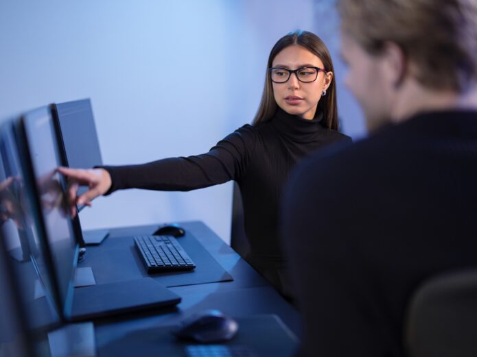 Cybersecurity professionals discussing and analyzing network security data on multiple screens in